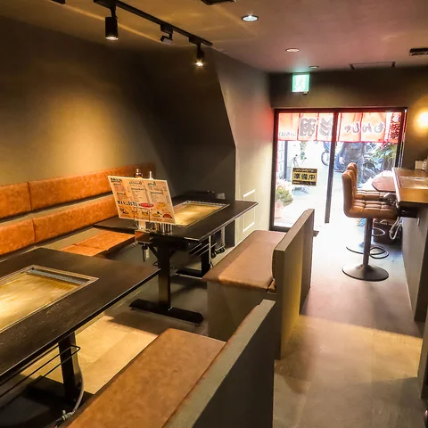 夜の駅前通りに面した店舗入口、暖簾と看板の明かりが見える外観